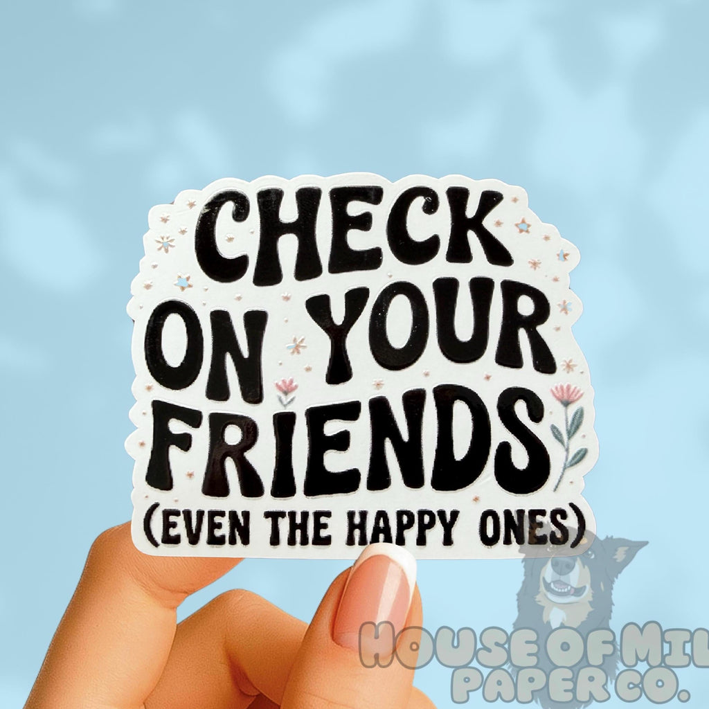 Sticker with text 'Check on your friends (even the happy ones)' held by a hand against a light blue background. Suicide Prevention and Awareness