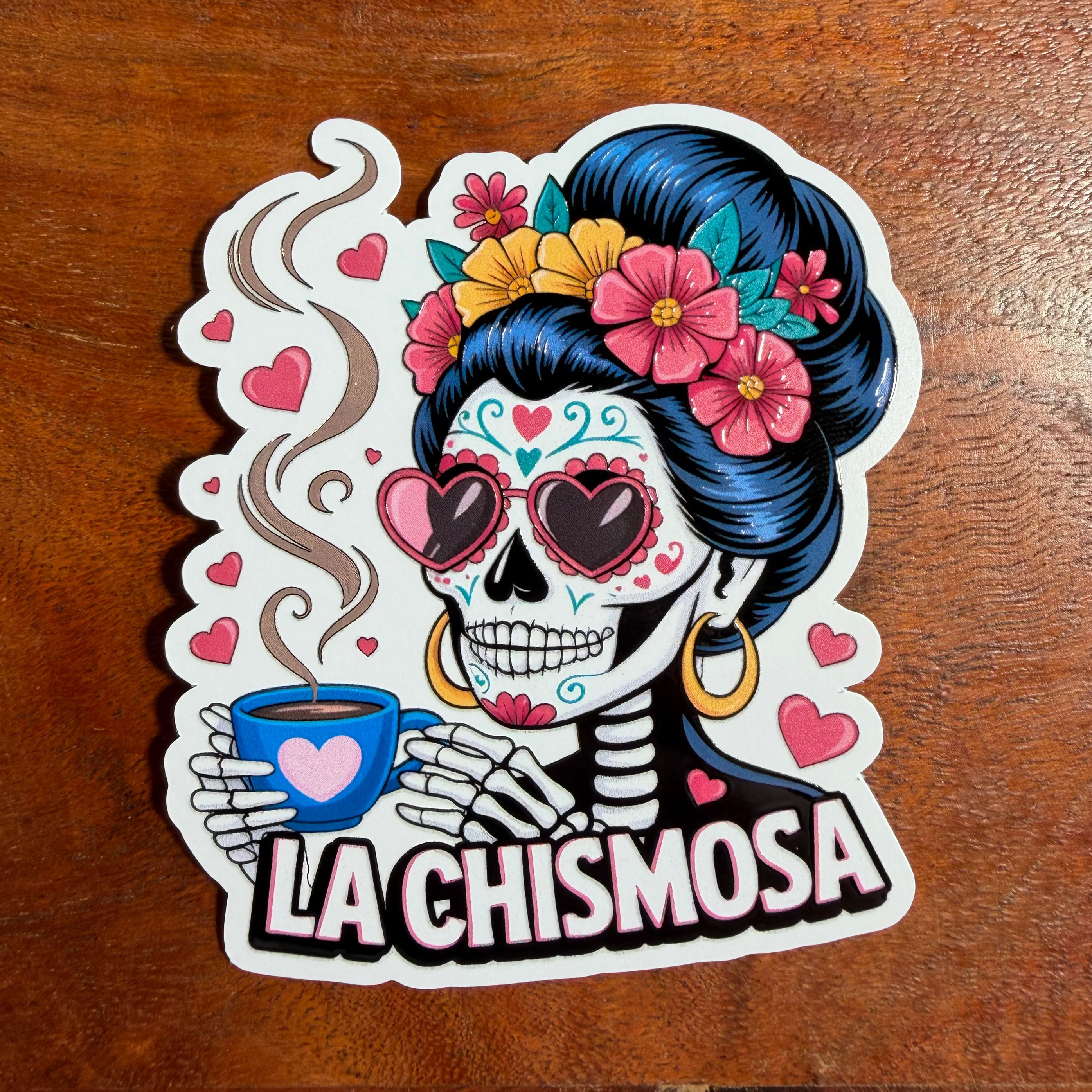 Sticker of a skeleton with floral hair and a coffee cup on a wooden surface