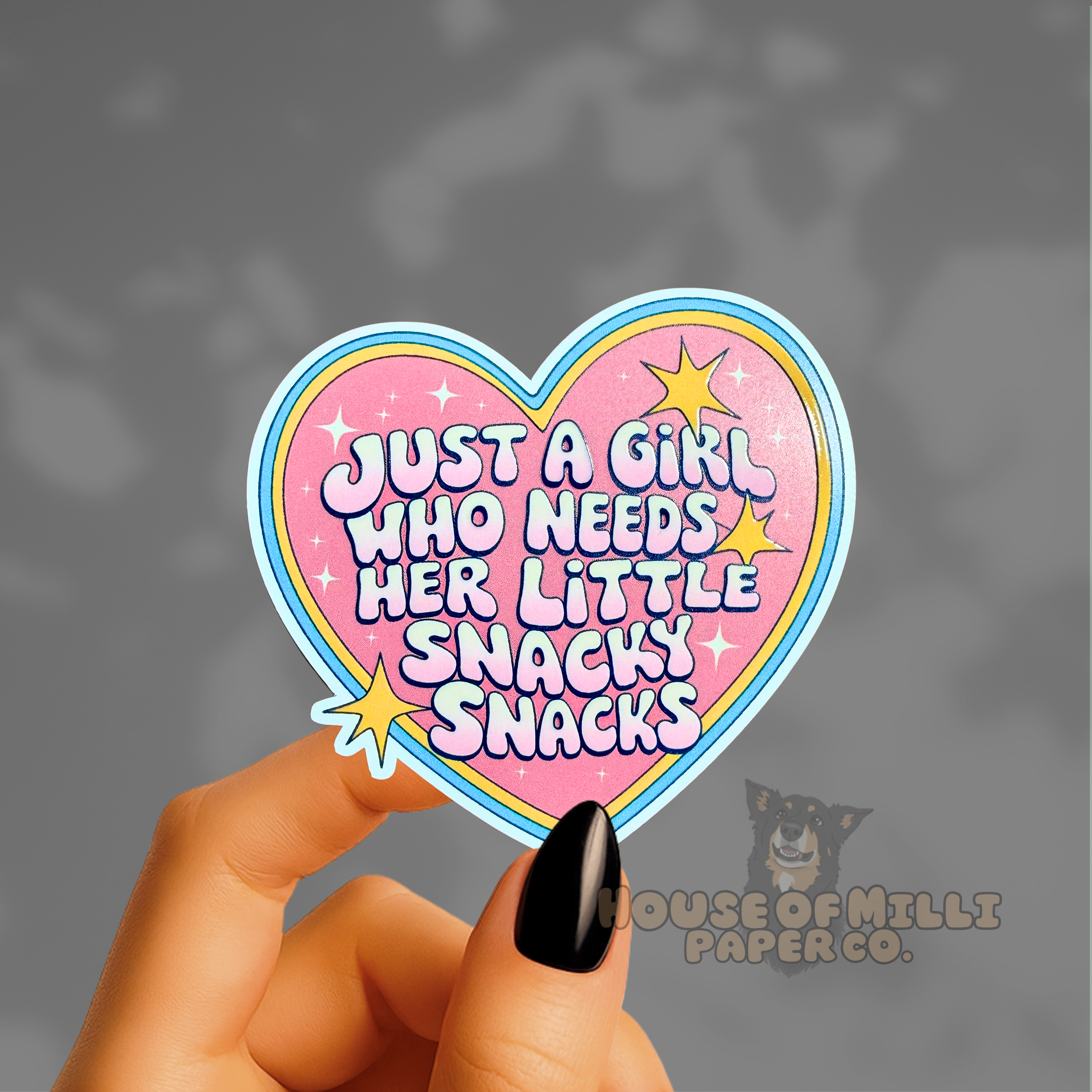 Heart-shaped sticker with text held by a hand against a dark background