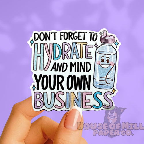 Sticker with text 'Don't forget to hydrate and mind your own business' held by a hand on a purple background.