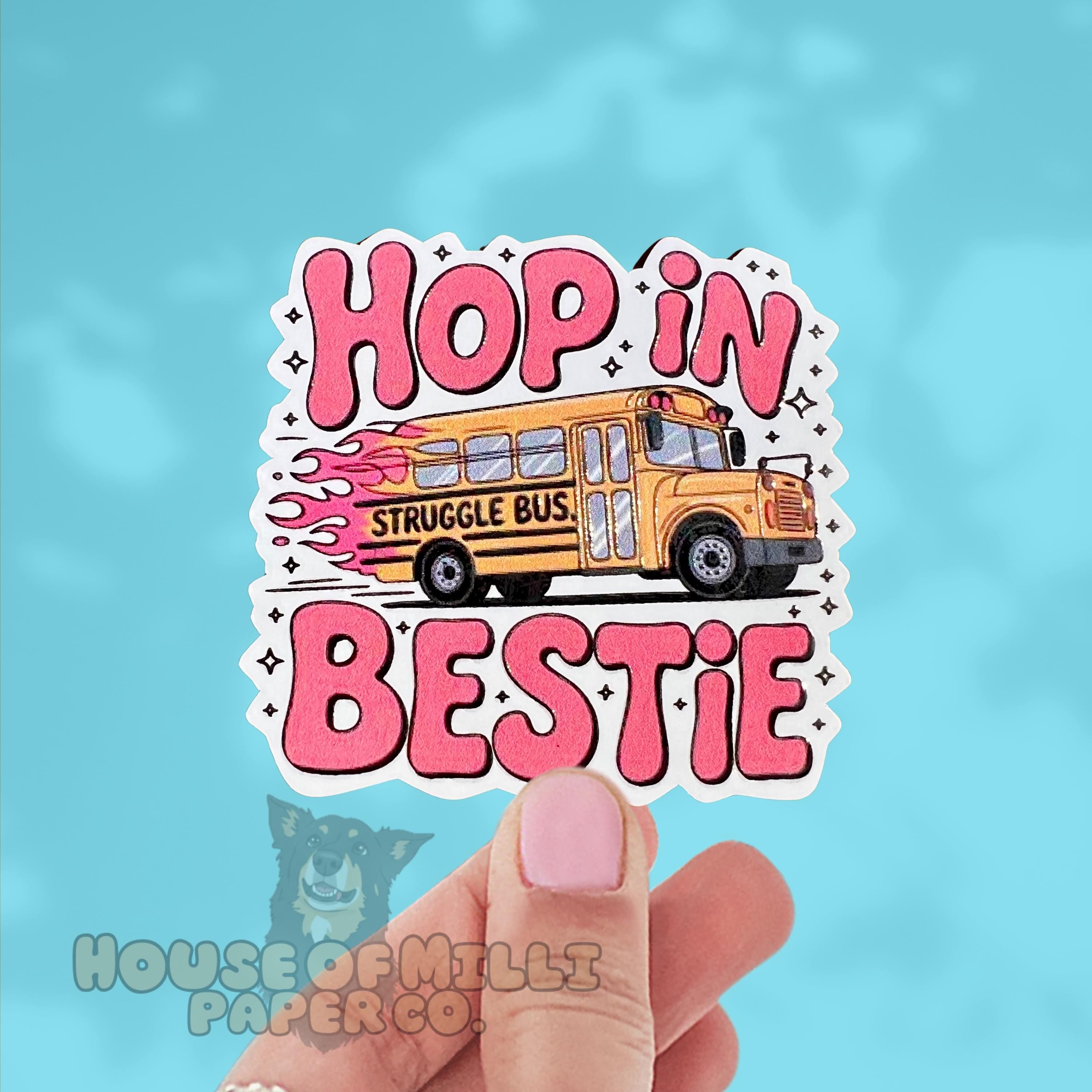 Sticker with a school bus and text 'Hop in Struggle Bus Bestie' held by a hand against a blue background.