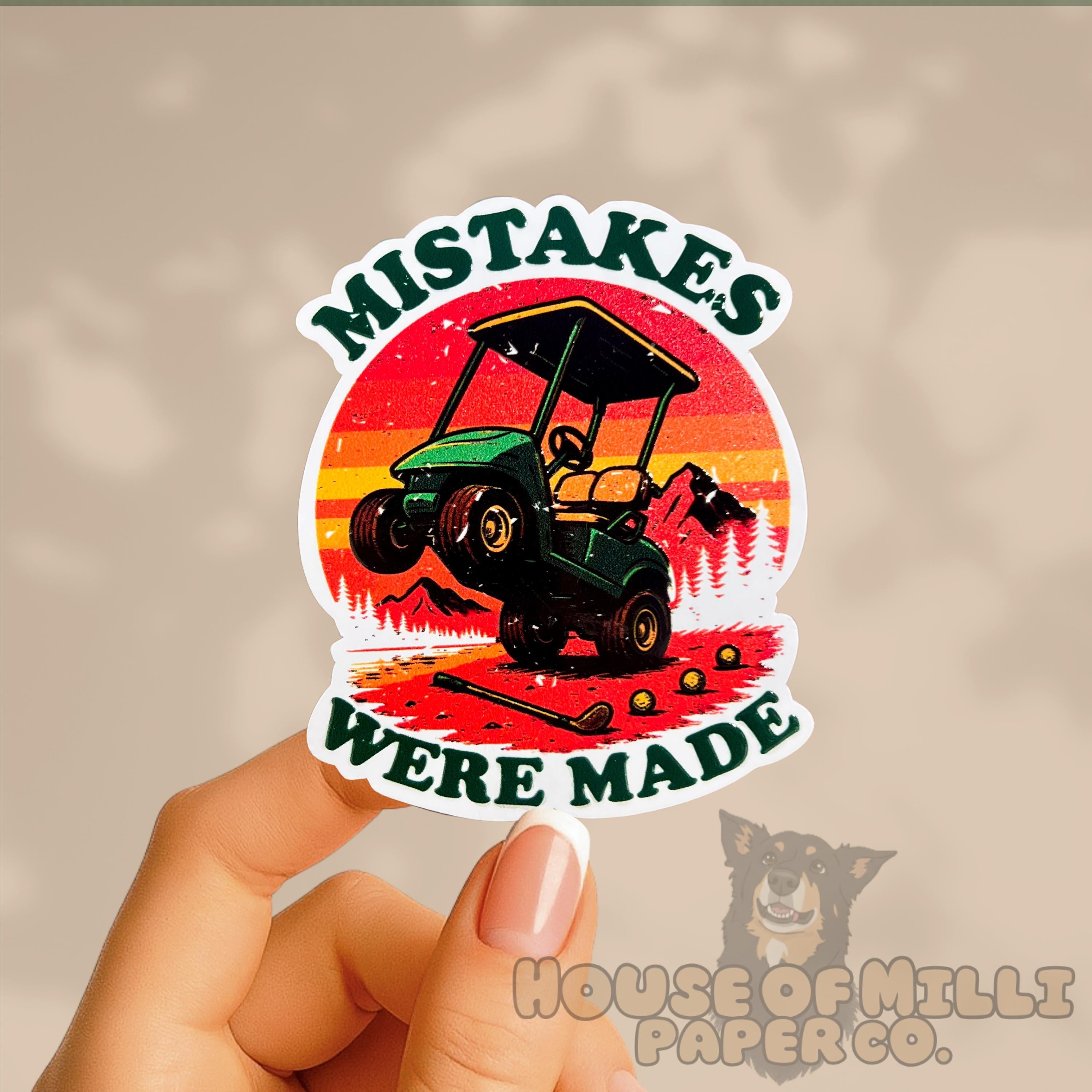 Sticker with a golf cart graphic and text 'Mistakes Were Made' held by a hand.