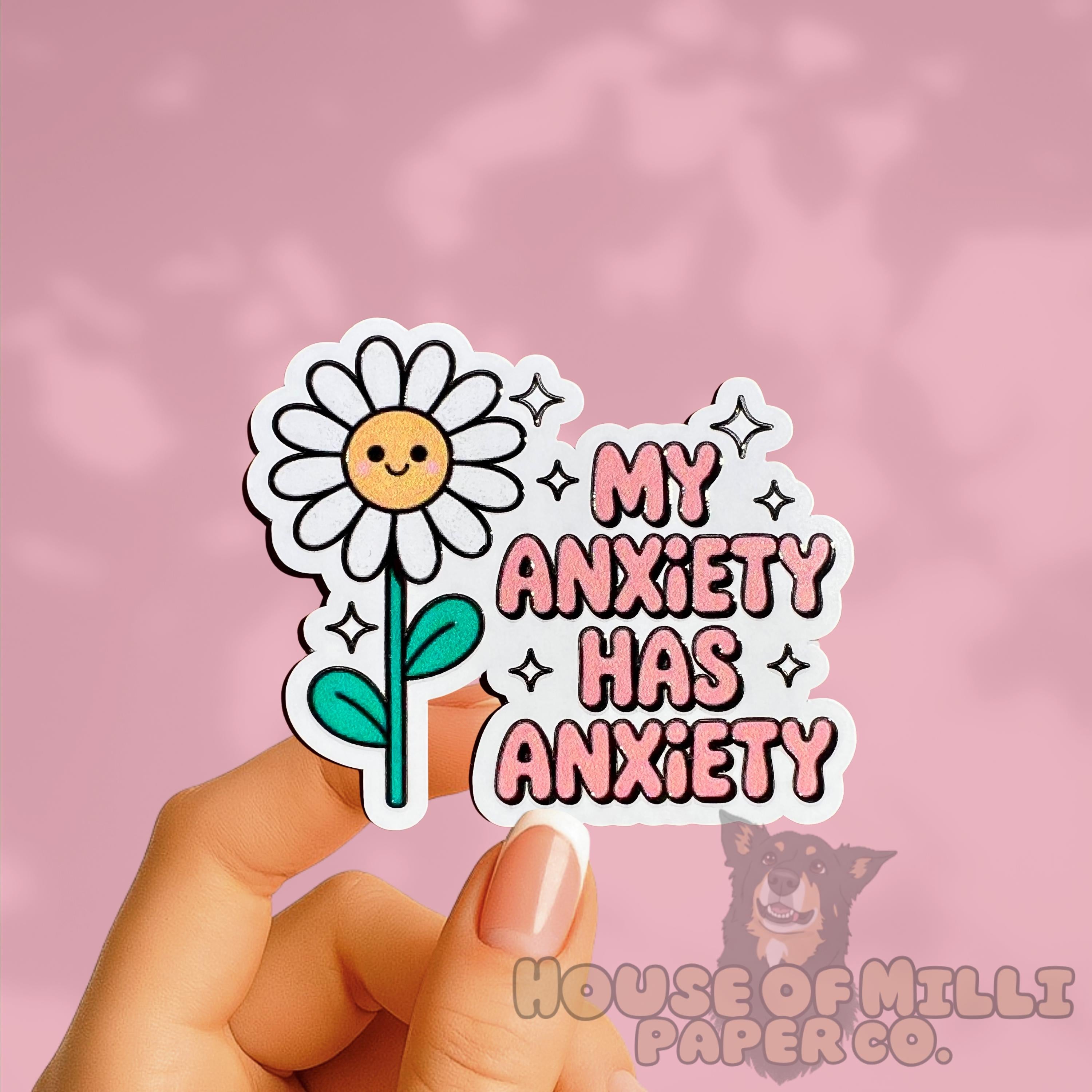 Sticker with a flower and 'My Anxiety Has Anxiety' text held by a hand on a pink background.